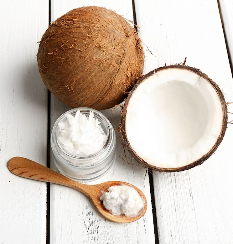 Coconut Oil in a spoon next to a whole coconut