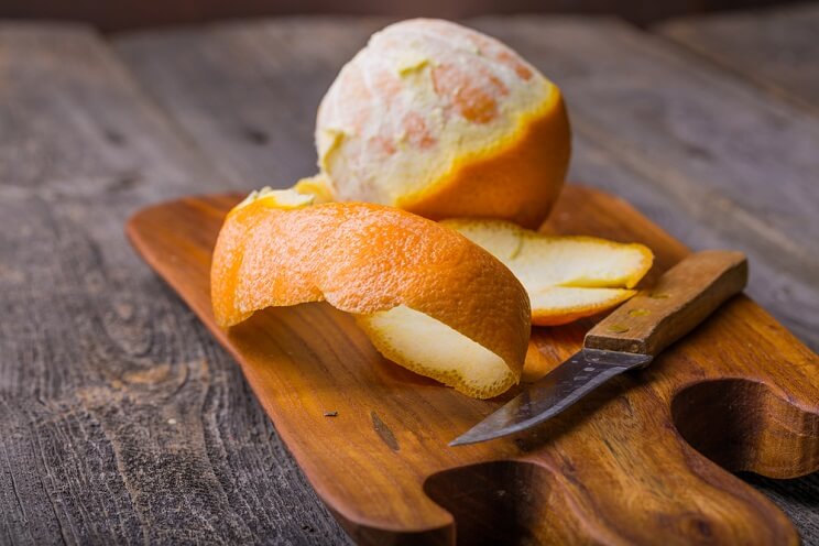 orange peel and a knife on cutting board
