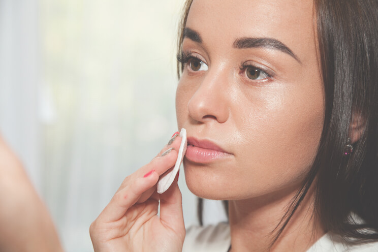 woman applying makeup with cotton pad