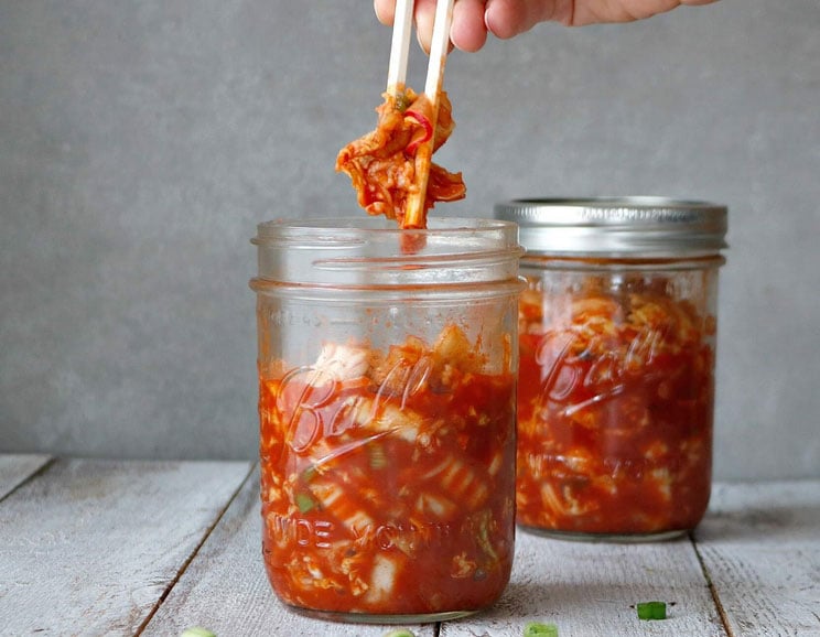 Shredded cabbage ferments with radishes, scallions, and ginger for a homemade, Paleo-friendly kimchi rich in gut-healing probiotics.