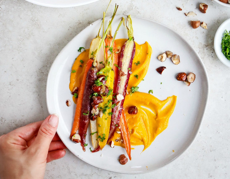 Honey-roasted rainbow carrots are served on top of a creamy sweet potato purée for an easy, elegant veggie dish. This side dish is anything but boring!